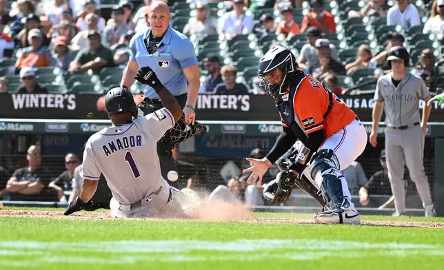 Colorado Rockies' Adael Amador (1) slides to score a run as Detroit Tigers catcher Eduardo Valencia looks at the ball during the sixth inning of a baseball game, Saturday, Sept. 12, 2026, in Detroit. (AP Photo/Jose Juarez)