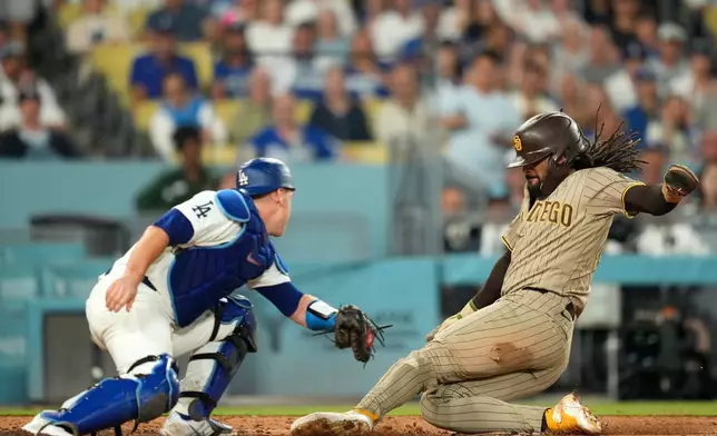 San Diego Padres' Fernando Tatis Jr., right, scores on a sacrifice fly by Manny Machado as Los Angeles Dodgers catcher Will Smith makes a late tag during the fifth inning of a baseball game Wednesday, Sept. 23, 2026, in Los Angeles. (AP Photo/Mark J. Terrill)