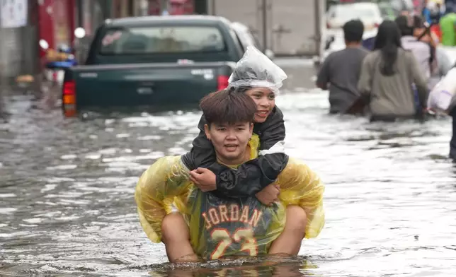 People wade through a flooded street after a heavy rain in Bangkok, Thailand, Monday, Sept. 28, 2026. (AP Photo/Sakchai Lalit)