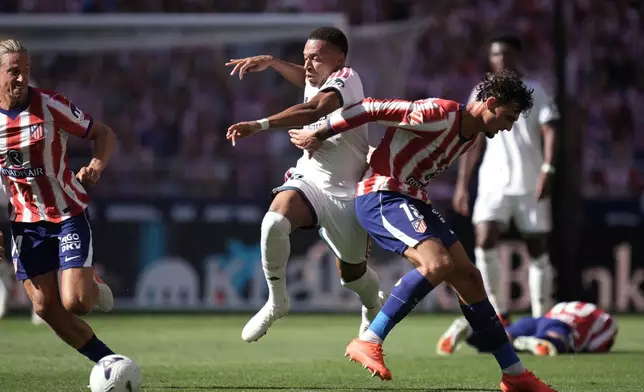 Real Madrid's Kylian Mbappe tries to get past Atletico Madrid's Marc Pubill, right, and Marcos Llorente during a Spanish La Liga soccer match between Atletico Madrid and Real Madrid in Madrid, Sunday, Sept. 20, 2026. (AP Photo/Bernat Armangue)