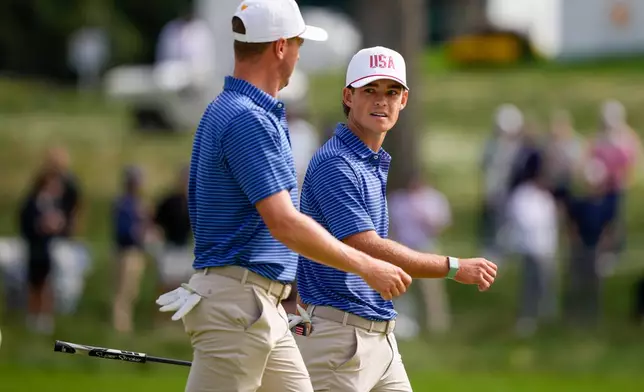 USA teams' Justin Thomas talks with Jackson Koivun, right, on the seventh green during the first round four-ball match at the Presidents Cup golf tournament against the International team at Medinah Country Club, Thursday, Sept. 24, 2026, in Medinah, Ill. (AP Photo/Matt Slocum)