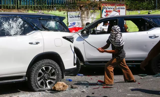 A man attacks a vehicle from an opposing group outside a school used as a polling center during the Bangsamoro Autonomous Region in Muslim Mindanao parliamentary elections in Cotabato city, southern Philippines, Monday, Sept. 14, 2026. (AP Photo)