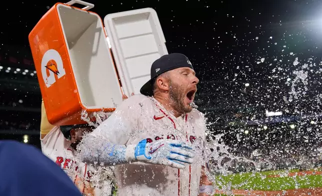 Boston Red Sox's Trevor Story is doused with a cooler of ice water after his game-winning, RBI single in the bottom ninth inning of a baseball game against the Seattle Mariners, Monday, Aug. 31, 2026, in Boston. (AP Photo/Charles Krupa)