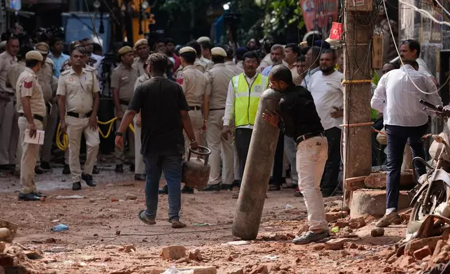 A rescue worker carries a cylinder at the site of a collapsed building in New Delhi, India, Monday, Sept. 7, 2026. (AP Photo/Manish Swarup)