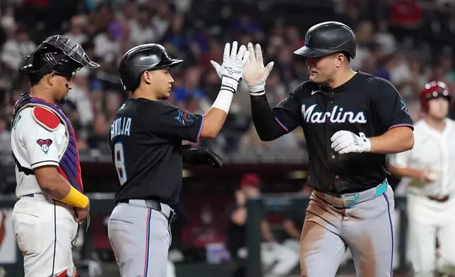 Miami Marlins' Jakob Marsee, right, celebrates his two-run home run with Marlins' Javier Sanoja (8) as Arizona Diamondbacks catcher Gabriel Moreno, left, pauses at home plate during the third inning of a baseball game, Wednesday, Sept. 16, 2026, in Phoenix. (AP Photo/Ross D. Franklin)