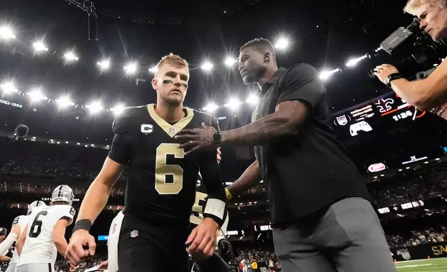 New Orleans Saints quarterback Tyler Shough (6) is greeted by former player Benjamin Watson, right, after the coin toss during the first half of an NFL football game against the Las Vegas Raiders in New Orleans, Sunday, Sept. 27, 2026. (AP Photo/Gerald Herbert)