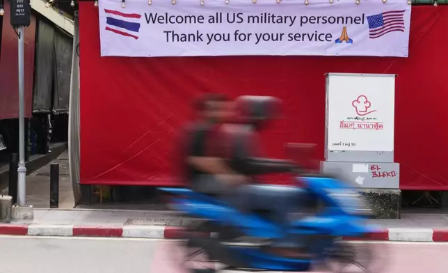 A motorcycle taxi drives past a banner in Pattaya, Thailand, Tuesday, Sept. 1, 2026. (AP Photo/Sakchai Lalit)