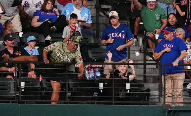 A fan attempts to reach a three-run home run ball hit by Boston Red Sox's Trevor Story in the eighth inning of a baseball game against the Texas Rangers Thursday, Sept. 17, 2026, in Arlington, Texas (AP Photo/Tony Gutierrez)