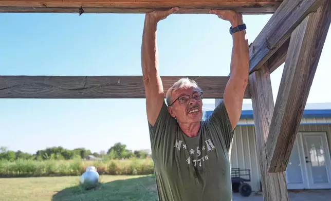 Ed Westrick, 59, adjusts a roof on a small building at his rural home near Commerce, Texas, Friday, Sept. 18, 2026. (AP Photo/LM Otero)