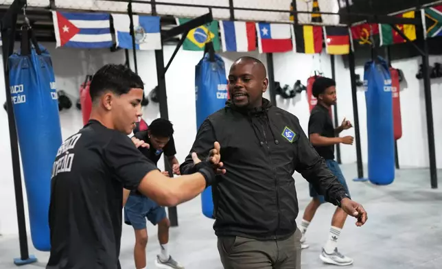Owner Alan Duarte greets a youth at Abraco Campeao, or Embrace Champions, an academy that offers free boxing, jiu-jitsu, Muay Thai and capoeira classes, as well as educational talks on topics ranging from environmental issues to relationships, in the Complexo de Alemao favela in Rio de Janeiro, Wednesday, Sept. 16, 2026. (AP Photo/Silvia Izquierdo)