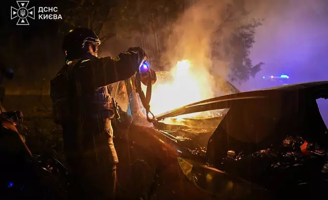 In this photo provided by the Ukrainian Emergency Services, a rescue worker checks a car destroyed following a Russian strike on Kyiv, Ukraine, Thursday, Sept. 24, 2026. (Ukrainian Emergency Service via AP)