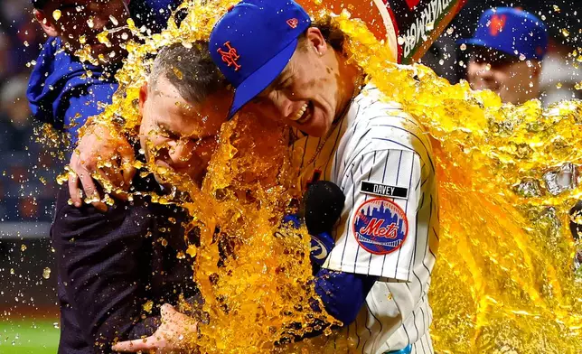New York Mets' Carson Benge, right, hugs announcer Steve Gelbs as he gets doused with Gatorade after breaking the Mets rookie season record for hits in New York, Saturday, Sept. 19, 2026. (AP Photo/Noah K. Murray)