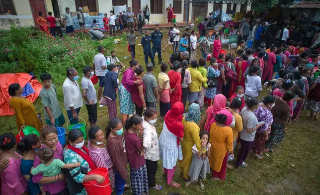 People affected by recent flash floods stand in line to receive aid at a school converted into a temporary shelter in Nepal’s Nuwakot district, Thursday, Sept. 3, 2026. (AP Photo/Rajesh Kumar Singh)