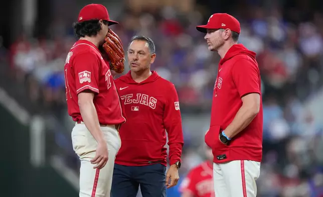 Texas Rangers starting pitcher Cal Quantrill, left, talks to head athletic trainer Matt Lucero, center, and pitching coach Jordan Tiegs during the second inning of a baseball game against the Toronto Blue Jays, Saturday, Sept. 19, 2026, in Arlington, Texas. (AP Photo/Julio Cortez)