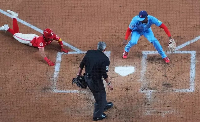 Texas Rangers' Nicky Lopez, left, prepares to slide into home ahead of the tag by Toronto Blue Jays starting pitcher JosÈ Soriano, right, as home plate umpire Manny Gonzalez looks on during the second inning of a baseball game Saturday, Sept. 19, 2026, in Arlington, Texas. (AP Photo/Julio Cortez)