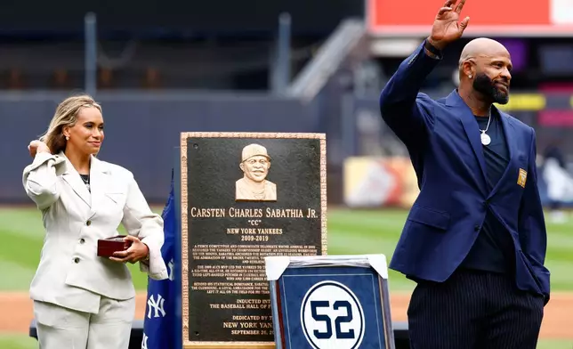 Hall of Famer CC Sabathia, right, waves as his wife Amber looks on during his Monument Park induction ceremony before a baseball game between the New York Yankees and Baltimore Orioles, Friday, Sept. 25, 2026, in New York. (AP Photo/Noah K. Murray)