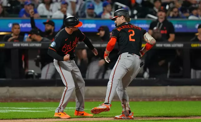 Baltimore Orioles third base coach Buck Britton, left, celebrates with Gunnar Henderson, right, as Henderson runs the bases after hitting a home run during the eighth inning of a baseball game against the New York Mets Monday, Sept. 14, 2026, in New York. (AP Photo/Frank Franklin II)