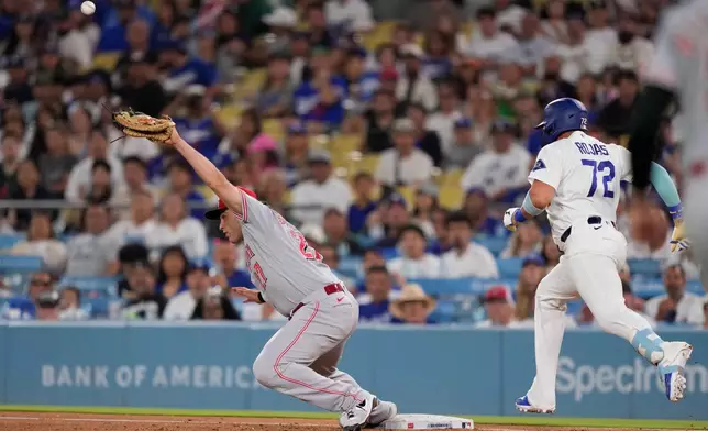 Los Angeles Dodgers' Miguel Rojas, right, makes it to first as Cincinnati Reds first baseman Sal Stewart misses the ball on a throwing error that allowed two runs to score during the fifth inning of a baseball game Monday, Sept. 7, 2026, in Los Angeles. (AP Photo/Mark J. Terrill)