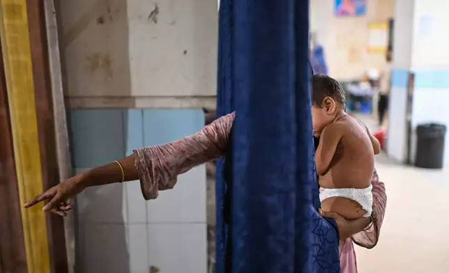 A woman brings her child for treatment of measles outbreak in a hospital in Dhaka, Bangladesh, Tuesday, Sept. 8, 2026. (AP Photo/Mahmud Hossain Opu)