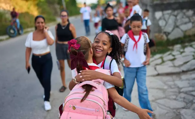 Girls hug as they arrive to school for their first day back to classes in Minas, Cuba's Havana province, Tuesday, Sept. 1, 2026. (AP Photo/Ramon Espinosa)