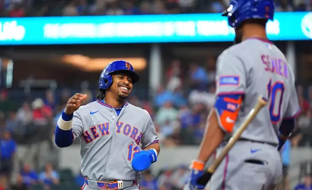 New York Mets' Francisco Lindor, left, is greeted near home plate by Marcus Semien after scoring on a single by teammate Carson Benge, not visible, during the first inning of a baseball game against the Texas Rangers, Thursday, Sept. 24, 2026, in Arlington, Texas. (AP Photo/Julio Cortez)