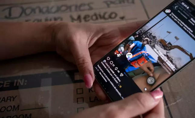 Dariela Merchan, a registered nurse, scrolls through the Instagram profile of an organization she is shipping supplies to in Venezuela for people recovering from June's twin earthquakes, at her home on Friday, Sept. 4, 2026, in Georgetown, Texas. (AP Photo/Joel Angel Juarez)