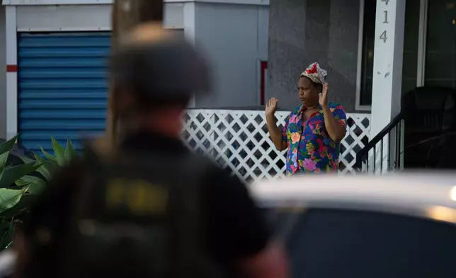 Lakiya Malone, charged with fraud involving federal homelessness aid programs, walks out of her home toward federal authorities with her hand raised in Los Angeles, Wednesday, Sept. 16, 2026. (AP Photo/Jae C. Hong)