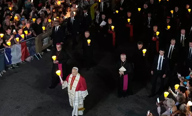 Pope Leo XIV, center, holds a candle during a prayer of Holy Rosary and torchlight procession at the Sanctuary of Our Lady of Lourdes, France, Sunday, Sept. 27, 2026. ((AP Photo/Laurent Cipriani)