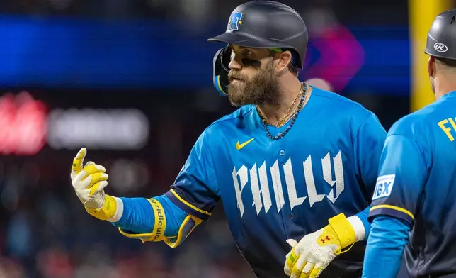 Philadelphia Phillies' Bryce Harper gestures from first base after hitting a single during the sixth inning of a baseball game against the Tampa Bay Rays, Friday, Sept. 25, 2026, in Philadelphia. (AP Photo/Laurence Kesterson)