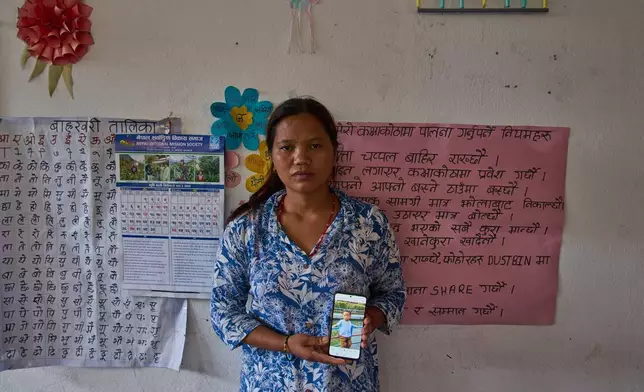 Pasang Maya Tamang stands inside a classroom converted into a temporary shelter as she shows a photograph of her 5-year-old son, who was swept away by flash floods, in Nepal's Nuwakot district, Tuesday, Sept. 8, 2026. (AP Photo/Dar Yasin)