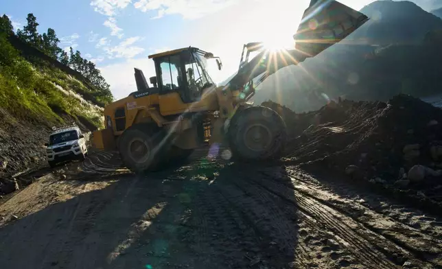 An excavator cuts into a hillside to build a temporary road connecting towns and villages after flash floods destroyed the existing road in Nepal's Nuwakot district, Tuesday, Sept. 22, 2026. (AP Photo/Niranjan Shrestha)