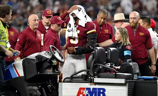 Trainers attend to Washington Commanders quarterback Jayden Daniels (5) after an apparent injury in the first half against the Dallas Cowboys during an NFL football game in Arlington, Texas, Sunday, Sept. 20, 2026. (AP Photo/Jessica Tobias)