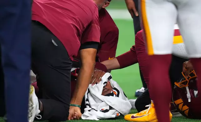 Trainers attend to Washington Commanders quarterback Jayden Daniels (5) after an apparent injury in the first half against the Dallas Cowboys during an NFL football game in Arlington, Texas, Sunday, Sept. 20, 2026. (AP Photo/Julio Cortez)