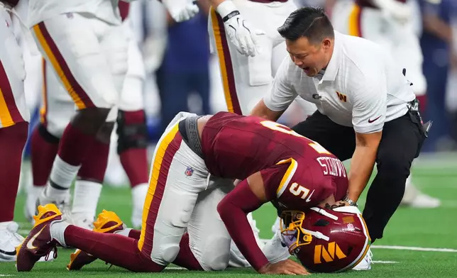 Washington Commanders quarterback Jayden Daniels (5) reacts after an apparent injury in the first half against the Dallas Cowboys during an NFL football game in Arlington, Texas, Sunday, Sept. 20, 2026. (AP Photo/Julio Cortez)