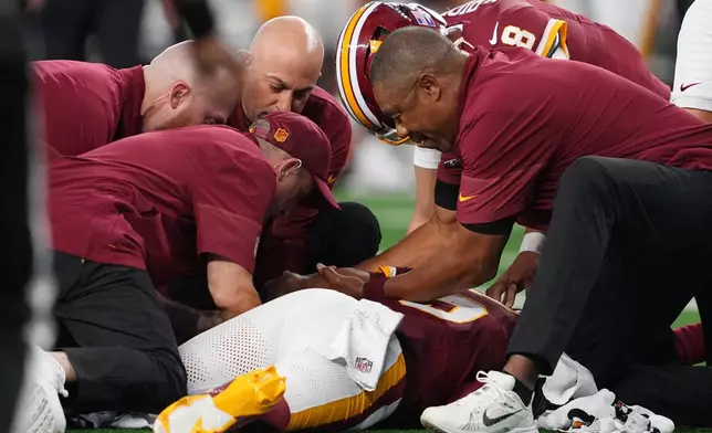 Trainers attend to Washington Commanders quarterback Jayden Daniels (5) after an apparent injury in the first half against the Dallas Cowboys during an NFL football game in Arlington, Texas, Sunday, Sept. 20, 2026. (AP Photo/Tony Gutierrez)