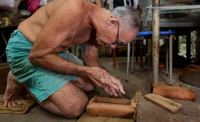 Traditional Chinese coffin maker Goh Khuay Par uses a hand tool to shape a miniature coffin at his workshop in Muar, Malaysia, Tuesday, July 14, 2026. (AP Photo/Vincent Thian)