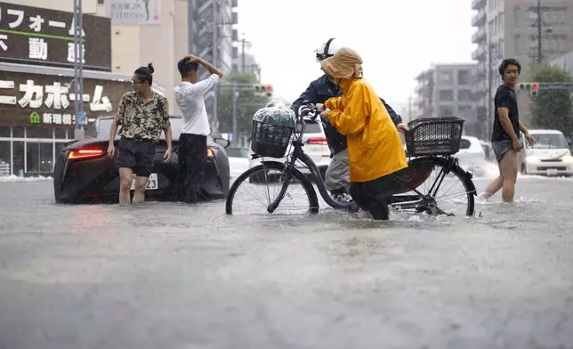 People cross the flooded streets following a heavy rain in Nagoya, central Japan Tuesday, Sept. 8, 2026. (Natsumi Yasumoto/Kyodo News via AP)