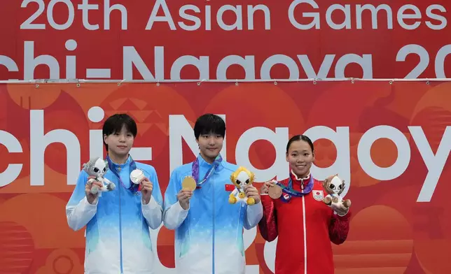 Gold medalist Yu Zidi of China, center, flanked by silver medalist Chang Mohan of China, left, and bronze medalist Misa Okuzono of Japan pose on the podium after the women's 200-meter butterfly final in swimming at the Asian Games in Tokyo, Japan, Sunday, Sept. 20, 2026. (AP Photo/Hiro Komae)