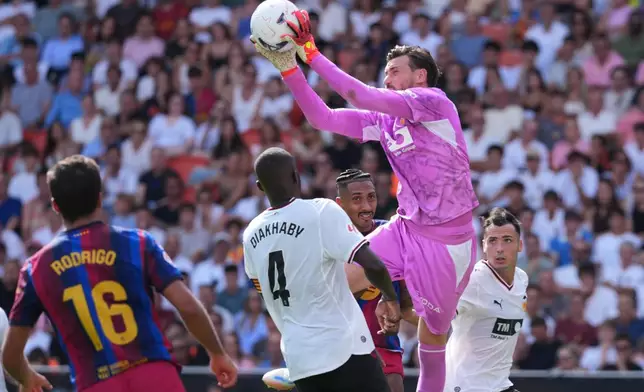 Valencia's goalkeeper Stole Dimitrievski jumps to catch the ball to make a save during the Spanish La Liga soccer match between Valencia and Barcelona in Valencia, Spain, Sunday, Sept. 6, 2026. (AP Photo/Alberto Saiz)