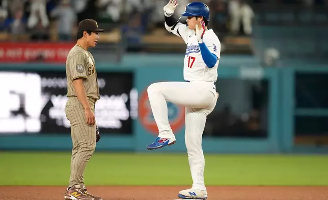 Los Angeles Dodgers' Shohei Ohtani, right, gestures after hitting a double as San Diego Padres second baseman Sung-Mun Song looks on during the ninth inning of a baseball game Thursday, Sept. 24, 2026, in Los Angeles. (AP Photo/Mark J. Terrill)