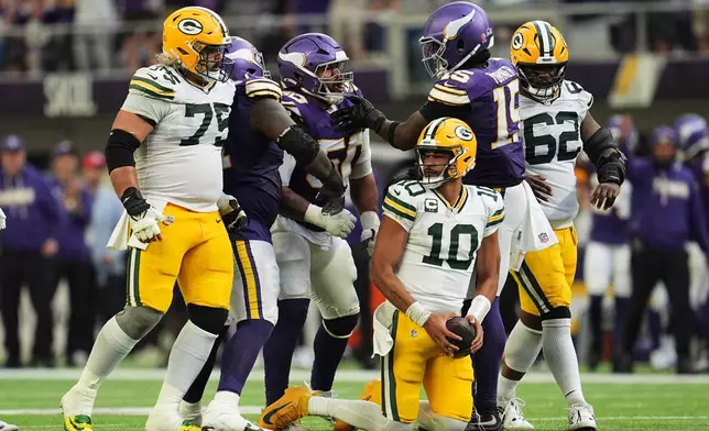 Green Bay Packers quarterback Jordan Love (10) recovers from being sacked by Minnesota Vikings' Levi Drake Rodriguez (50) who celebrates the play with Dallas Turner (15) during the second half of an NFL football game, Sunday, Sept. 13, 2026, in Minneapolis, Minn. (AP Photo/Abbie Parr)