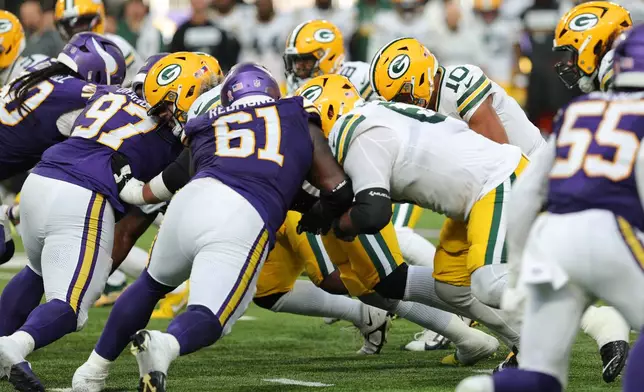 Minnesota Vikings' Domonique Orange (97) and Jalen Redmond (61) help stop Green Bay Packers quarterback Jordan Love (10) from running the ball for a first down during the second half of an NFL football game, Sunday, Sept. 13, 2026, in Minneapolis, Minn. (AP Photo/Bailey Hillesheim)