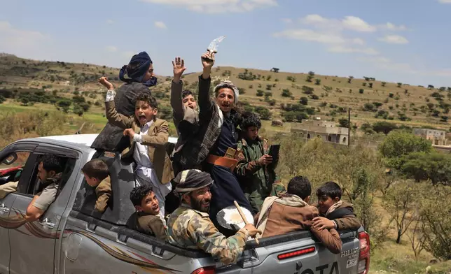 Yemeni civilians celebrate while riding in the back of a pickup truck in the Bani Matar district, Yemen, Saturday, Sept. 12, 2026, as they follow a convoy carrying Houthi prisoners freed in Mokha on its way to Sanaa following the Houthi takeover of the southern Red Sea port city. (AP Photo/STR)