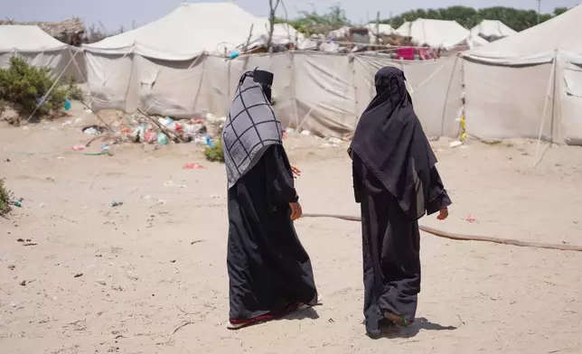 Displaced Yemenis, from Al Khawkhah city, 400 kilometers (249 miles) south west of Sanaa, walk past their temporary shelter in Aden, Yemen, Sunday, Sept. 13, 2026. (AP Photo/Abdulnasser Alseddik)
