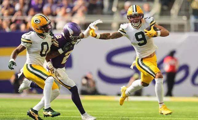 Green Bay Packers wide receiver Christian Watson (9) runs the ball for a touchdown after catching a pass as Matthew Golden (0) helps defend against a tackle attempt by Minnesota Vikings cornerback Isaiah Rodgers (2) during the first half of an NFL football game, Sunday, Sept. 13, 2026, in Minneapolis, Minn. (AP Photo/Abbie Parr)