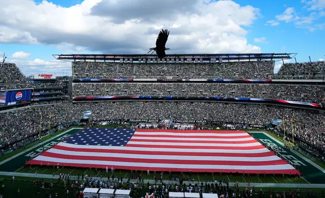 An eagle flies over a U.S. flag stretched out on the field for a 911 moment of silence before an NFL football game between the Philadelphia Eagles and the Washington Commanders, Sunday, Sept. 13, 2026, in Philadelphia. (AP Photo/Chris Szagola)
