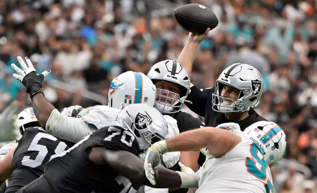 Las Vegas Raiders quarterback Kirk Cousins, right, throws a touchdown pass to running back Ashton Jeanty during the first half of an NFL football game against the Miami Dolphins, Sunday, Sept. 13, 2026, in Las Vegas. (AP Photo/David Becker)