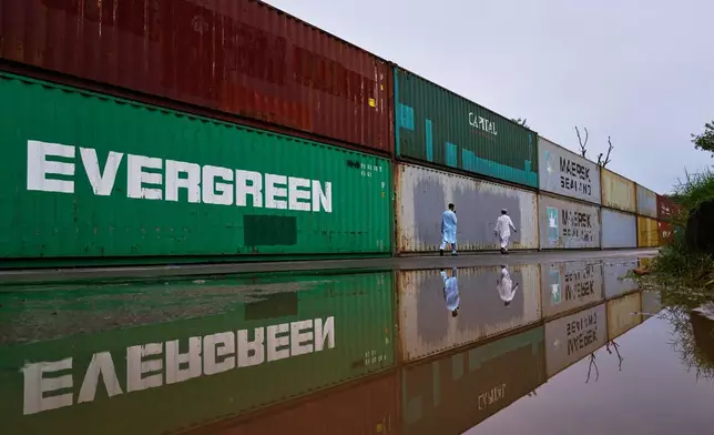 Residents walk past shipping containers placed by authorities to seal off an area ahead of a plan protest march by the supporters of imprisoned former Prime Minister Imran Khan demanding his release, in Islamabad, Pakistan, Monday, Sept. 28, 2026. (AP Photo/Anjum Naveed)