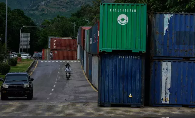 Motorcyclists drive past shipping containers placed by authorities to seal off an area ahead of a plan protest march by the supporters of imprisoned former Prime Minister Imran Khan demanding his release, in Islamabad, Pakistan, Monday, Sept. 28, 2026. (AP Photo/Anjum Naveed)
