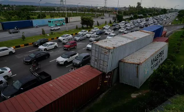 Vehicles drive past shipping containers placed by authorities along side on a highway for seal off an area ahead of a plan protest march by the supporters of imprisoned former Prime Minister Imran Khan demanding his release, in Islamabad, Pakistan, Monday, Sept. 28, 2026. (AP Photo/Anjum Naveed)